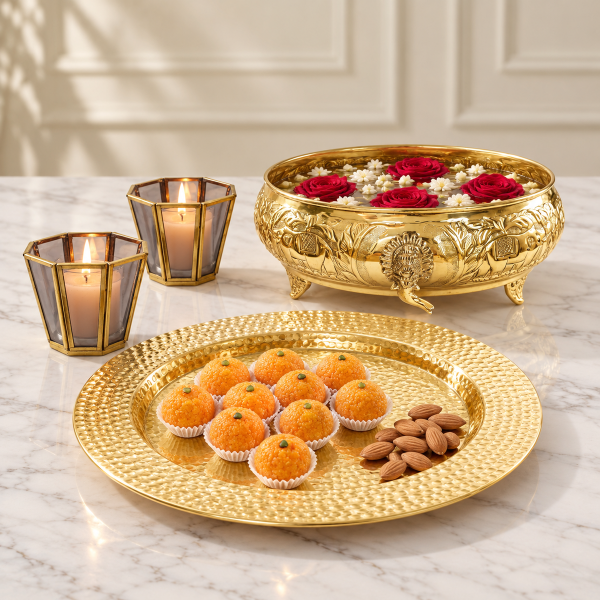 Gajgamini brass urli with gold hammered platter and two grey glass votive holders, photographed on marble