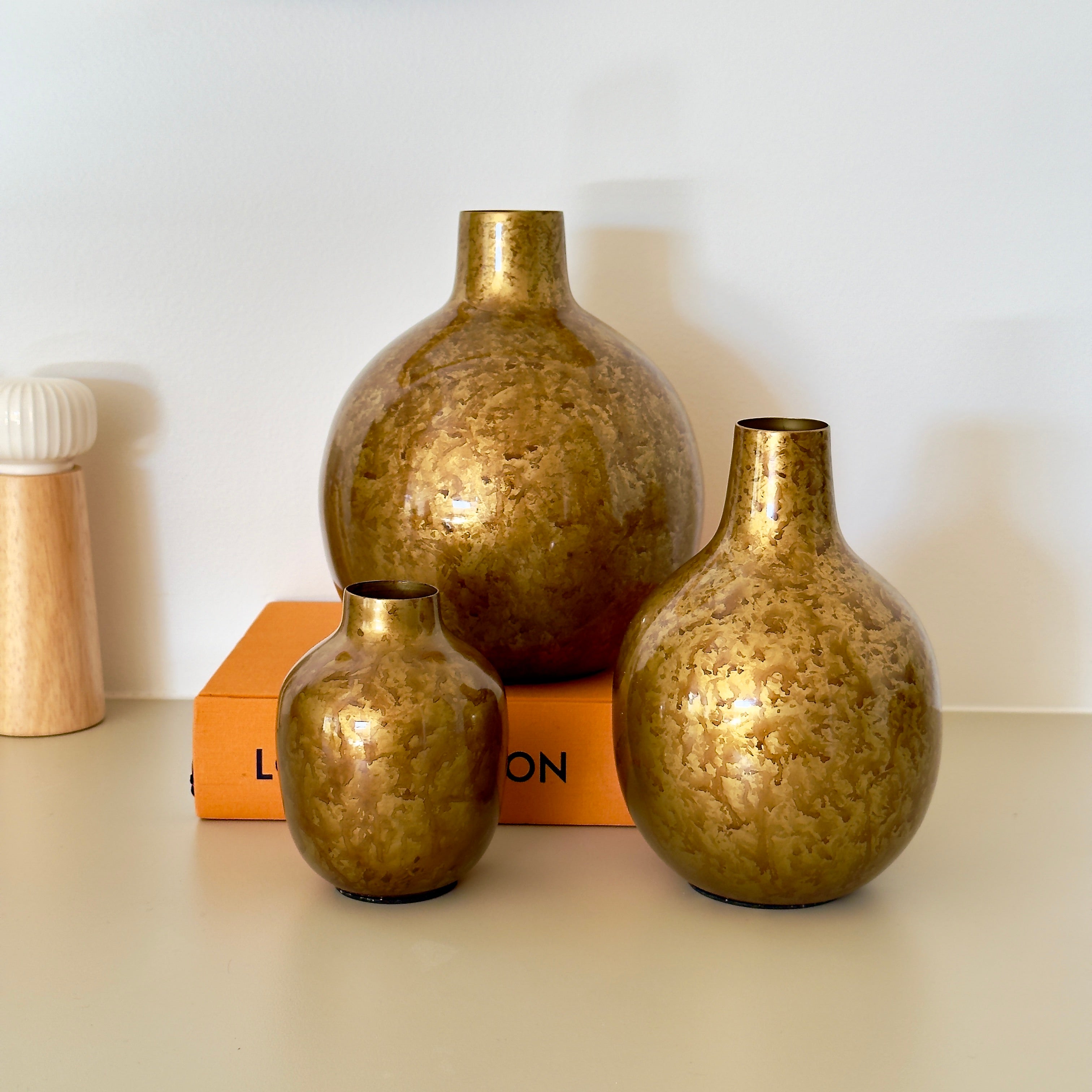 Product image of the Metal Bud Vase Set of 3 in Antique Gold from Indian Impressions, featuring a trio of elegantly designed vases with a vintage gold finish. Perfect for displaying single stems or as standalone décor pieces, these vases are ideal for Vastu, home décor, or gifting, adding a sophisticated and timeless touch to any space.