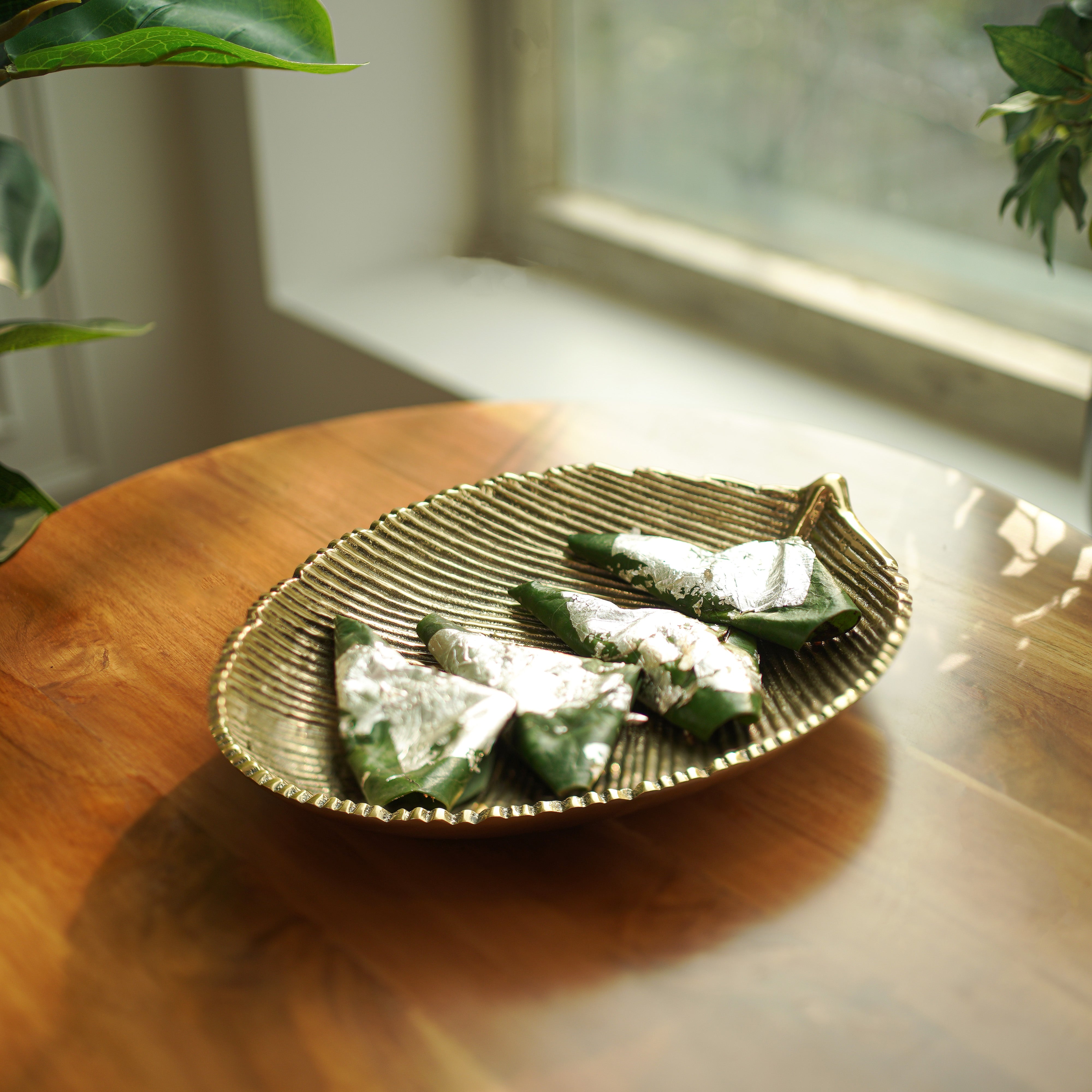 Delicious Paan on a decorative gold plate by a window with natural light.