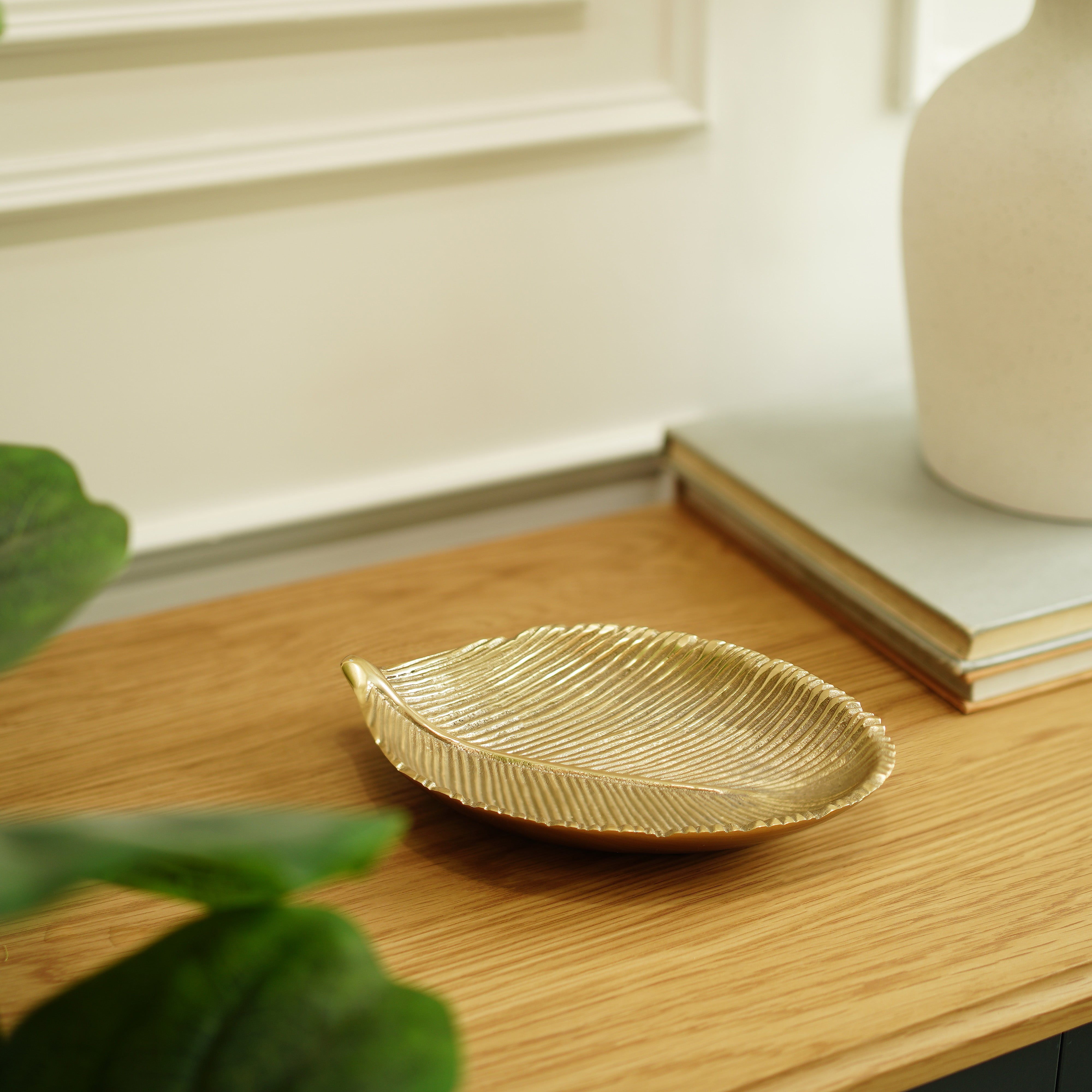 Gold leaf-shaped dish on a wooden surface with a blurred background