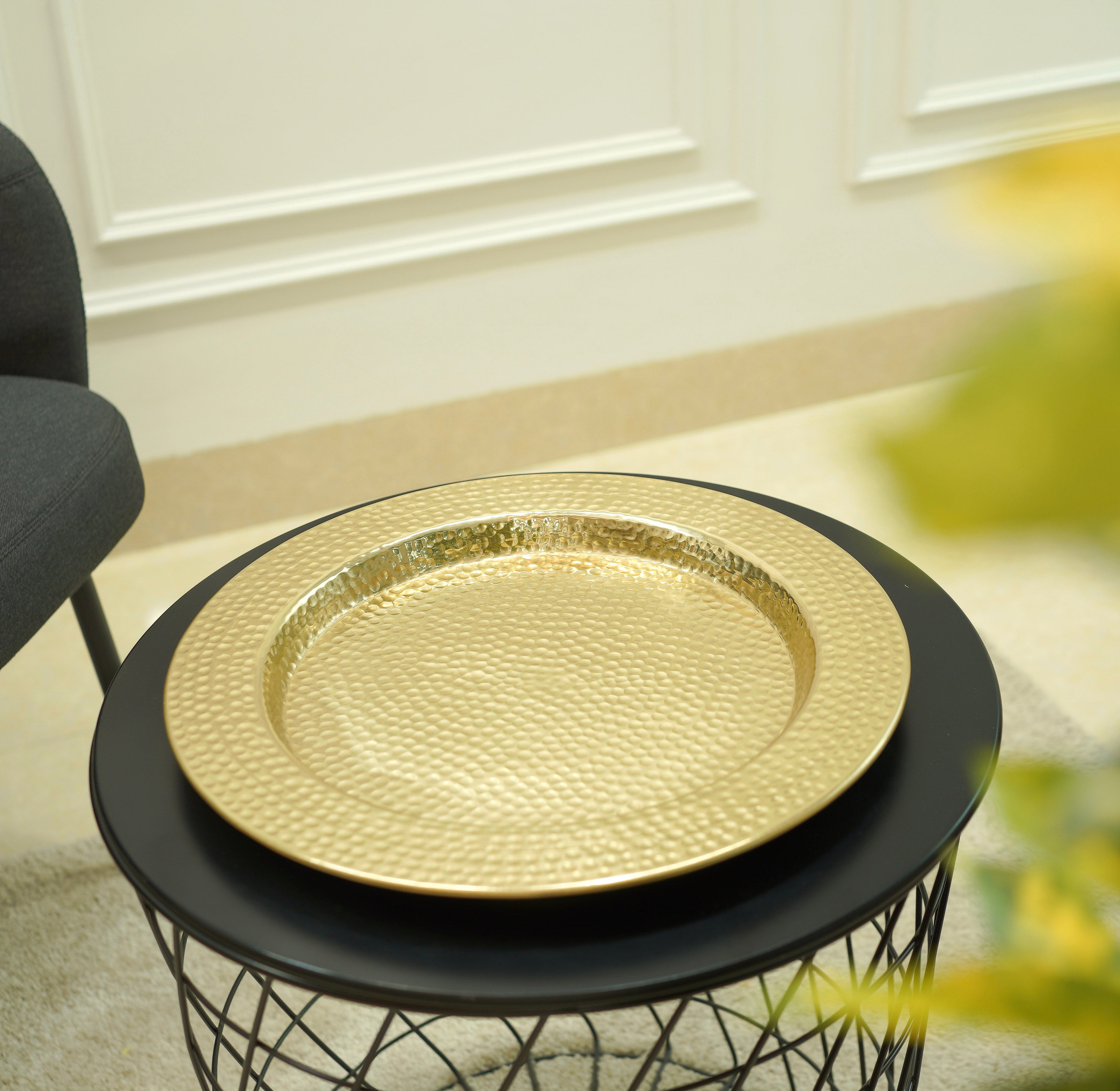 Gold decorative plate on a black round table with a blurred background