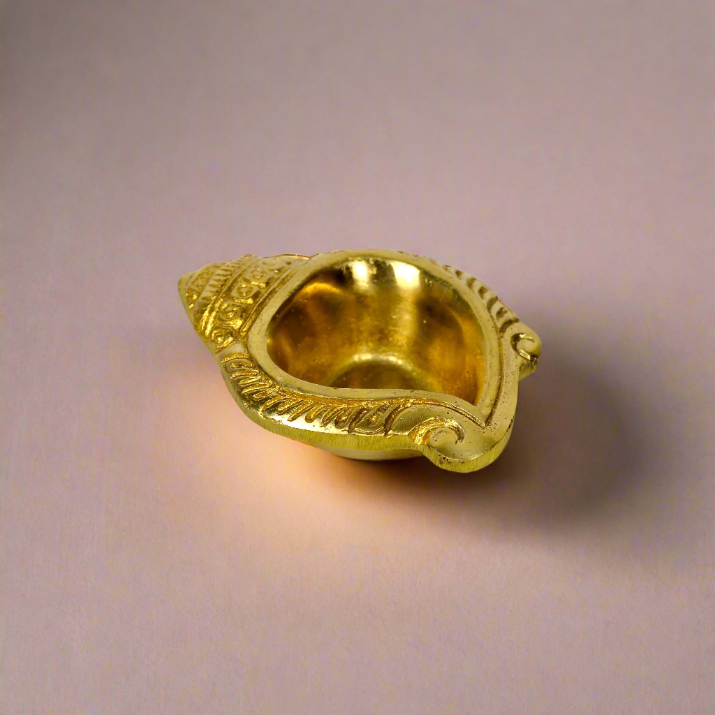 Product image of a Brass Shankh Diya from Indian Impressions, featuring a beautifully crafted conch shell design with intricate detailing. Made from polished brass, this diya is perfect for Vastu, spiritual rituals, home décor, or gifting, symbolizing purity, positivity, and divine energy.