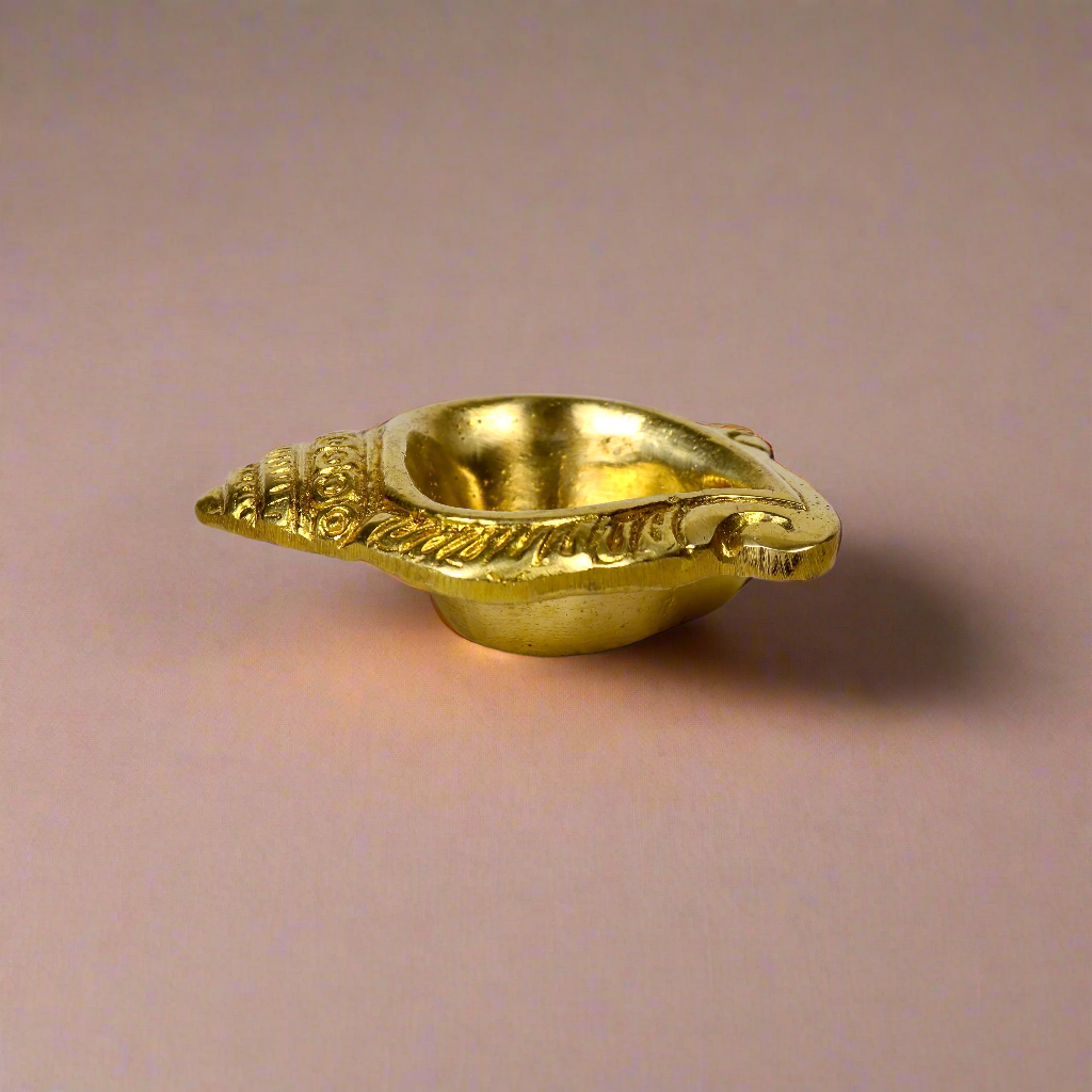 Product image of a Brass Shankh Diya from Indian Impressions, featuring a beautifully crafted conch shell design with intricate detailing. Made from polished brass, this diya is perfect for Vastu, spiritual rituals, home décor, or gifting, symbolizing purity, positivity, and divine energy.