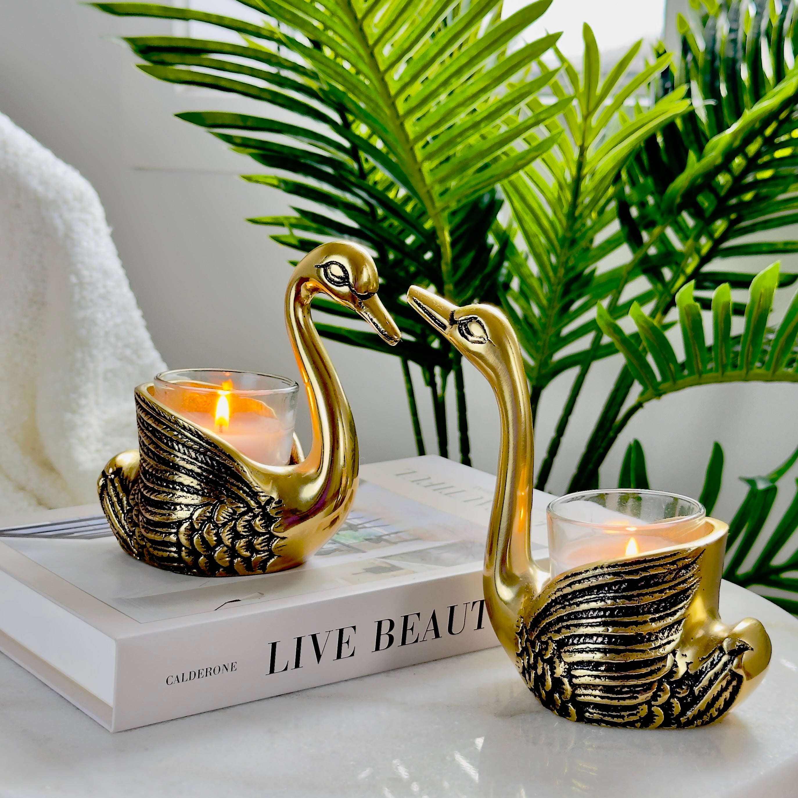 Product image of the Swan Figurine Candle Holder Pair in Gold from Indian Impressions, showcasing two intricately crafted swan-shaped candle holders with a polished gold finish. Ideal for holding candles, this elegant pair is perfect for Vastu, home décor, festive occasions, or gifting, adding sophistication and charm to any space.