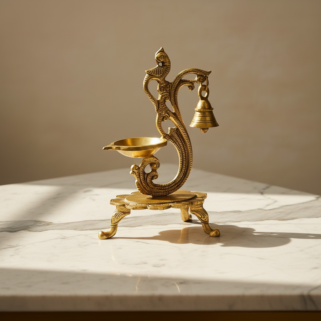 A brass oil lamp holder with a hanging bell and decorative serpent motif, displayed on a white marble surface with warm sunlight and shadows.