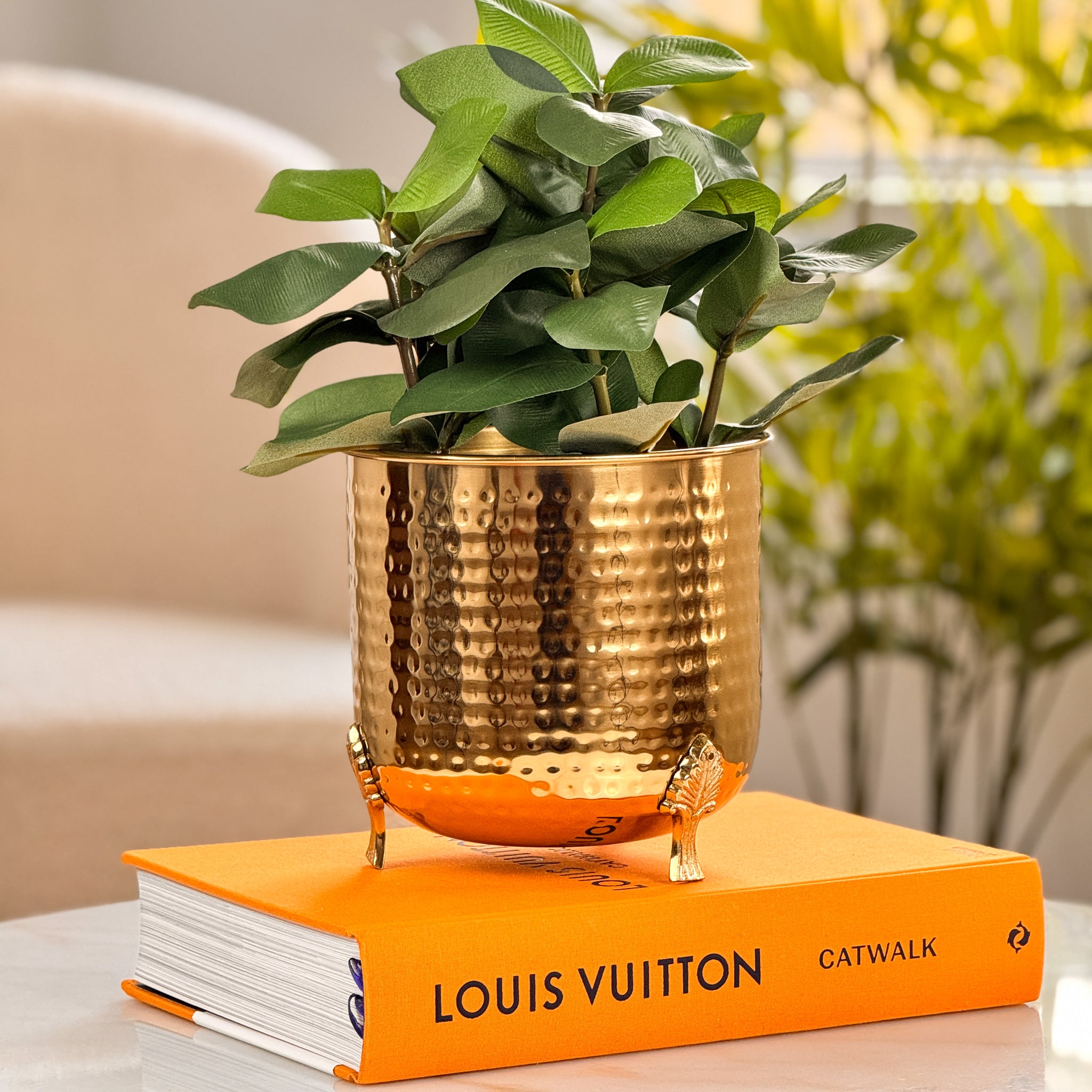 Product image of a Hammered Leaf Leg Planter in Gold from Indian Impressions, featuring a unique hammered texture and a leaf-patterned design. The planter comes with sturdy legs, crafted for elegance and stability. Ideal for enhancing Vastu energy, home décor, or gifting, this piece adds a modern yet traditional charm to any space.