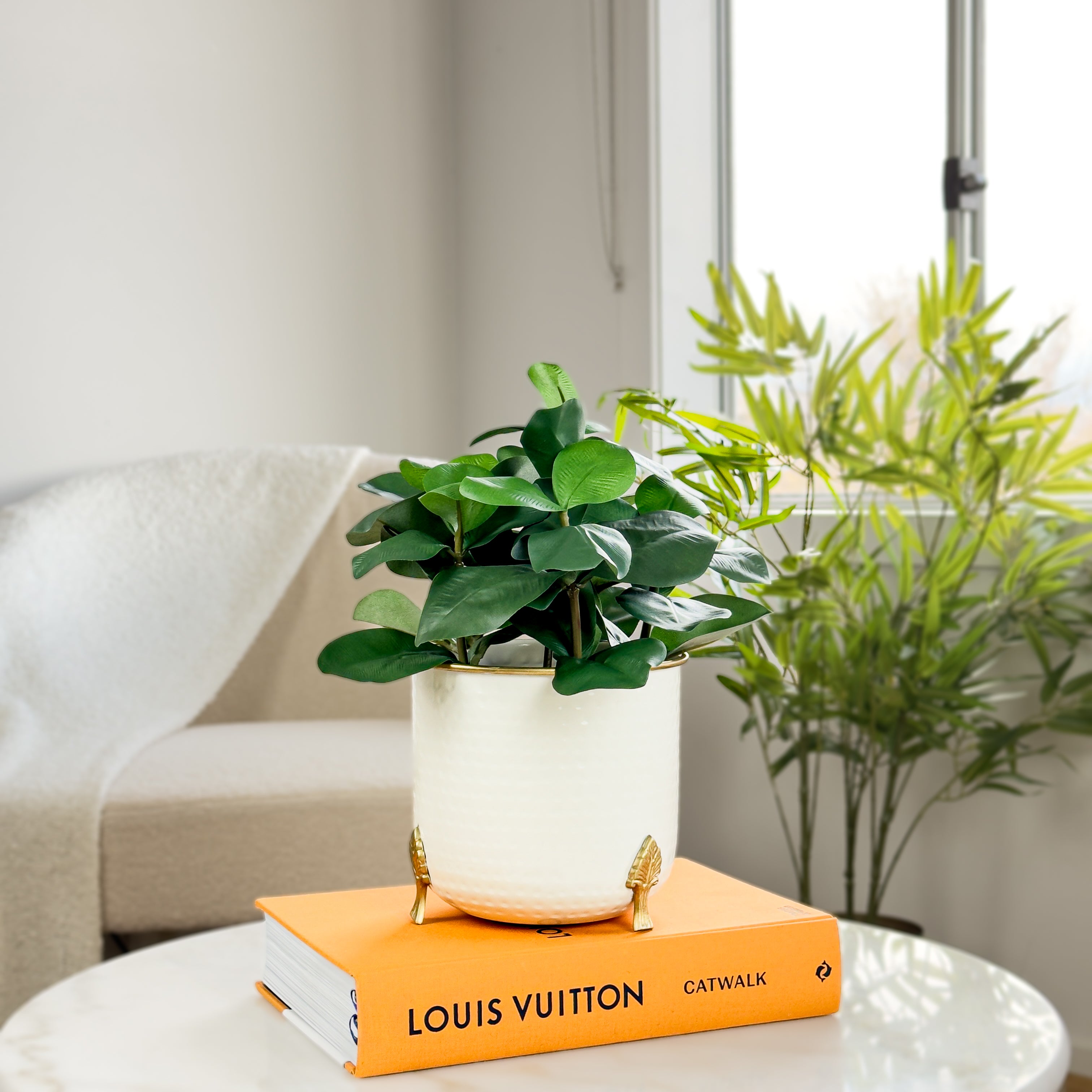 Product image of a Metal Hammered Gold Rim Leaf Leg Planter in White from Indian Impressions, featuring a sleek white body with a hammered texture and a gold rim for an elegant finish. Supported by sturdy leaf-patterned legs, this planter is ideal for enhancing Vastu energy, modern home décor, or gifting, adding sophistication to any space.