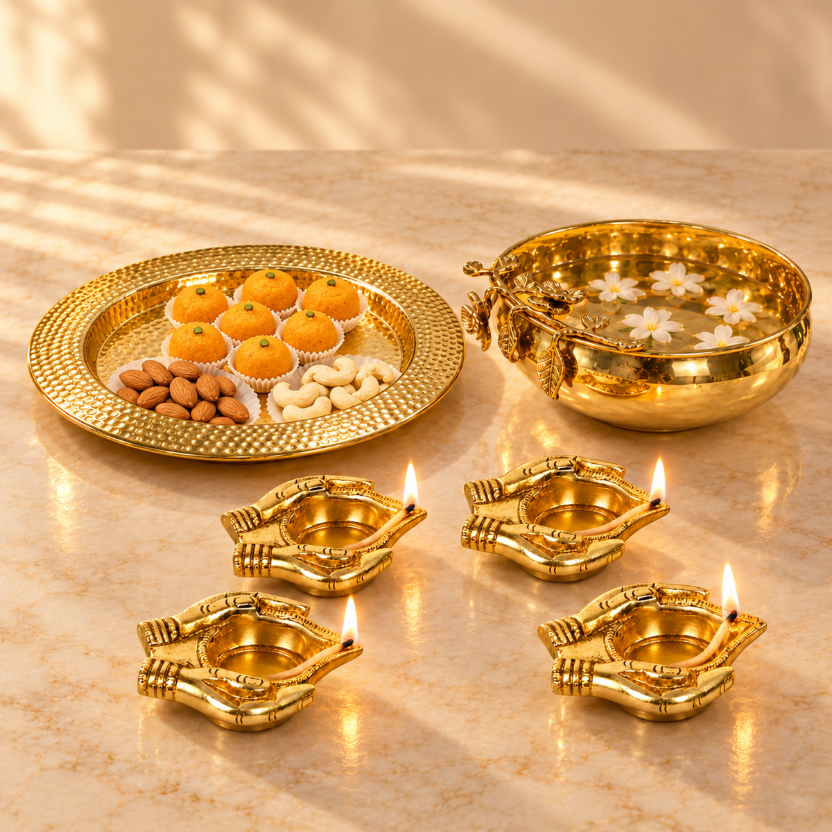 Mehak Brass Urli Signature Set - large gold urli with floating flowers, hammered gold platter of sweets and four lit brass bhakti deepak lamps