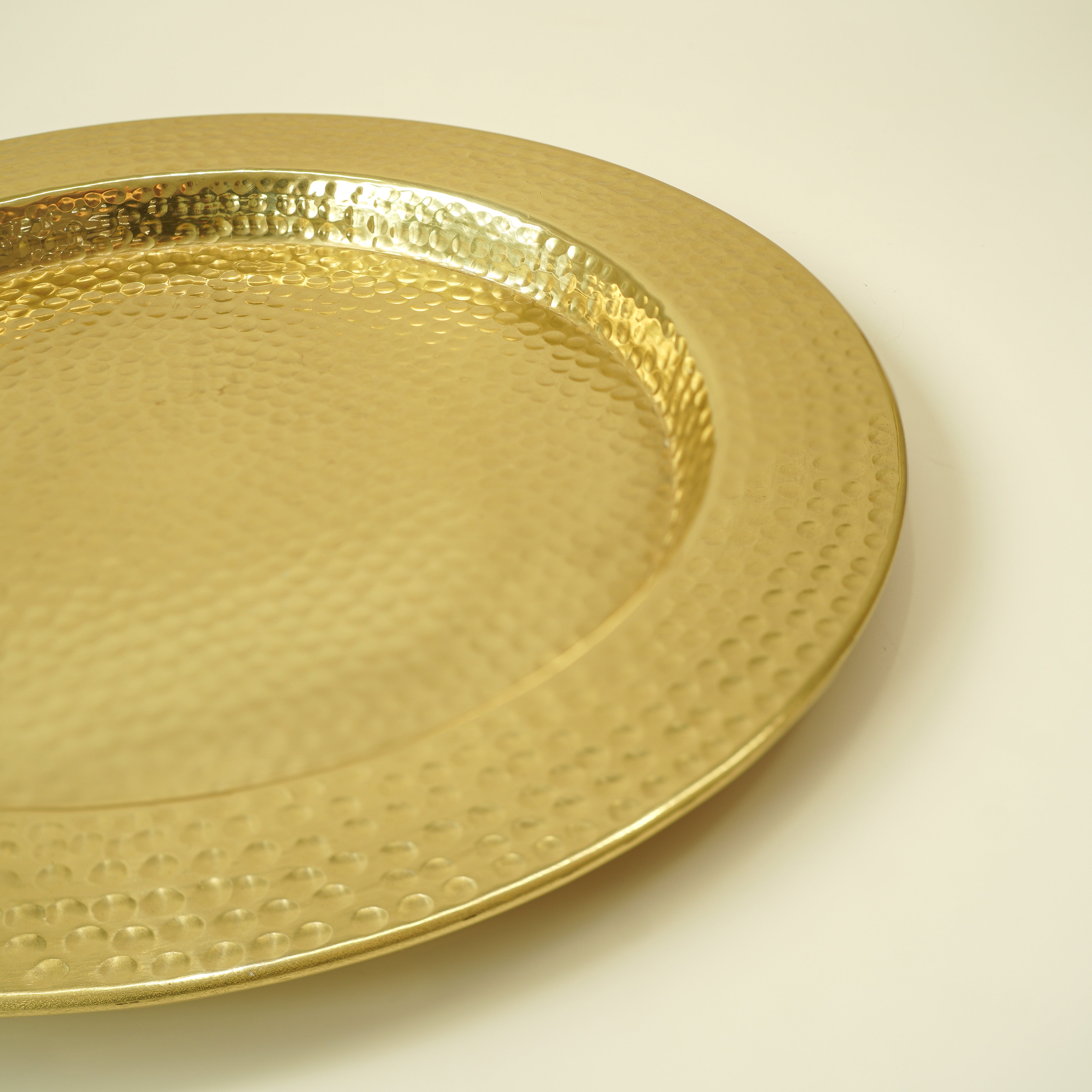 Gold metallic tray with textured surface on a beige background
