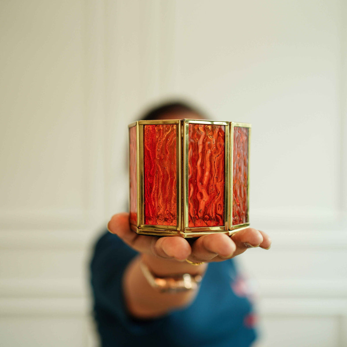Orange glass votive holder lit with a tealight on a styled table
