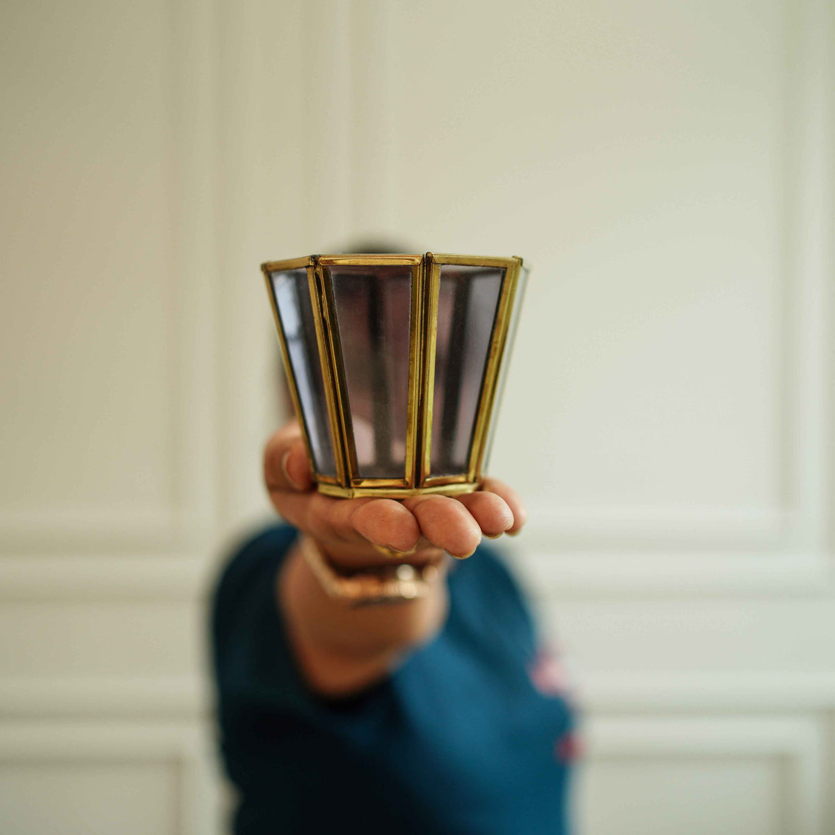 Grey glass votive holders styled as a pair beside gold decor
