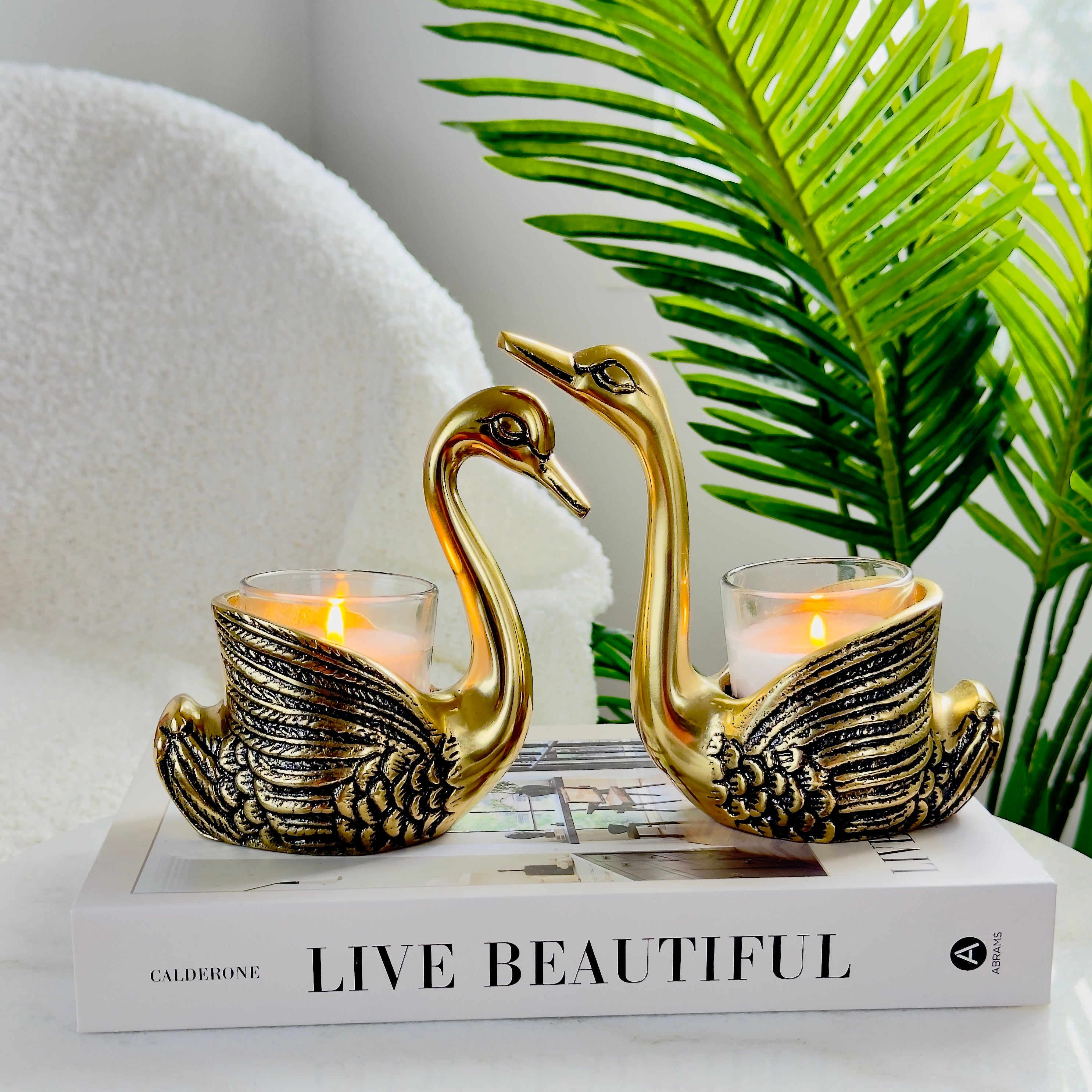 Product image of the Swan Figurine Candle Holder Pair in Gold from Indian Impressions, showcasing two intricately crafted swan-shaped candle holders with a polished gold finish. Ideal for holding candles, this elegant pair is perfect for Vastu, home décor, festive occasions, or gifting, adding sophistication and charm to any space.